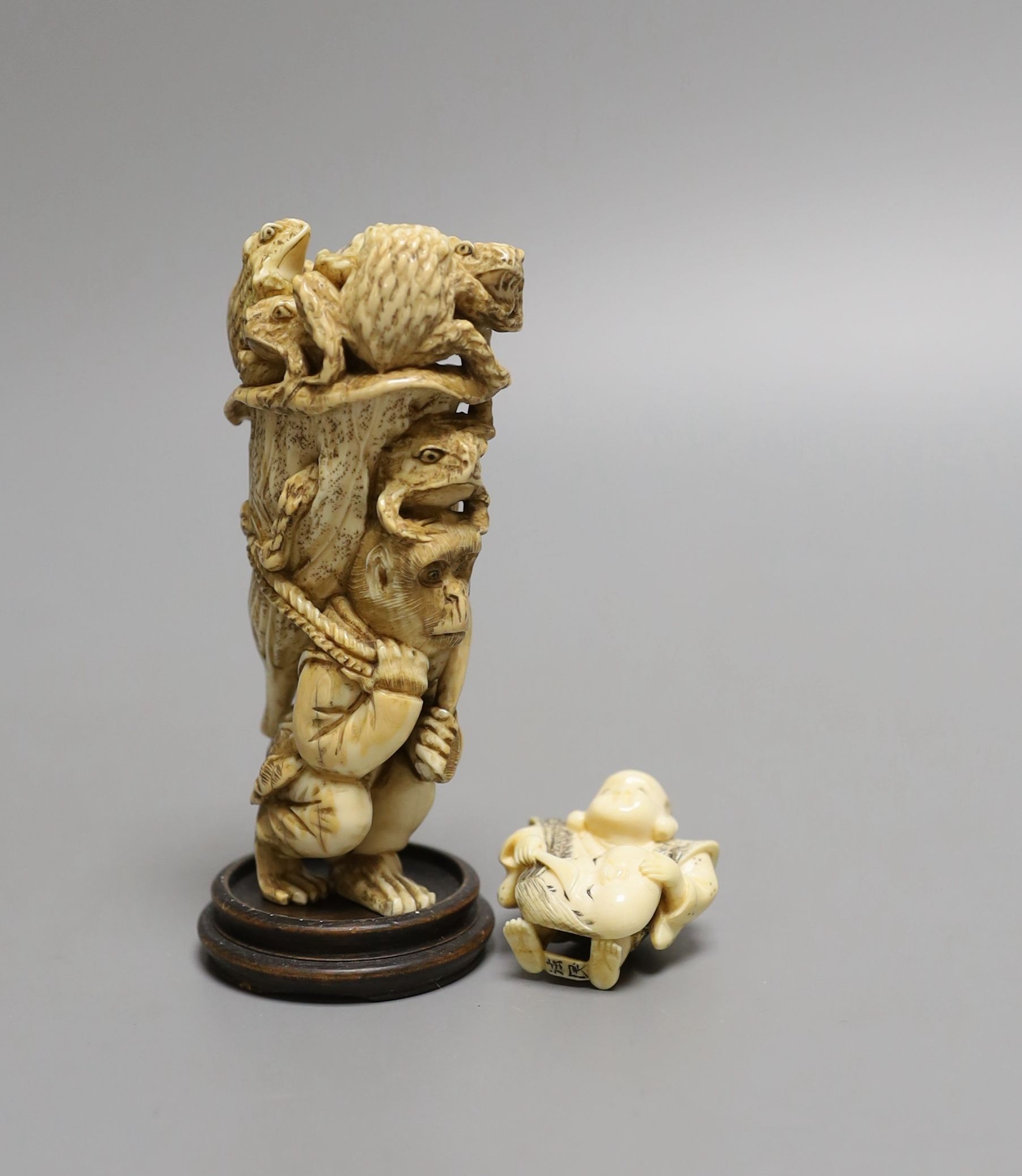 A Japanese ivory okimono of a monkey carrying a lotus leaf containing toads, on its back and an Ivory Netsuke of a mask maker, both Meiji period - tallest 9.5cm high